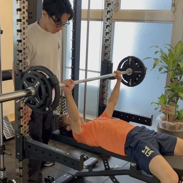 ベンチプレスをするお客様を、そばで見守るトレーナー