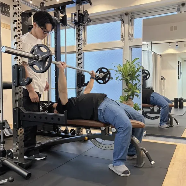 ベンチプレスをするお客様を、そばで補助するトレーナー